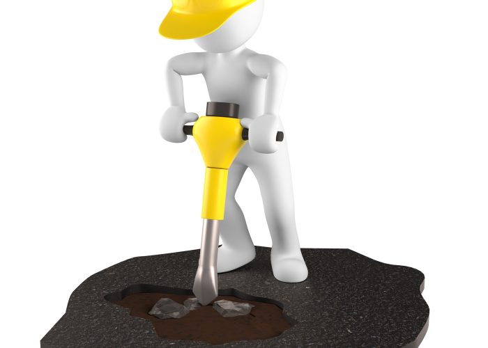 Pracownik w żółtym kasku trzyma w ręku młot i remontuje asfalt